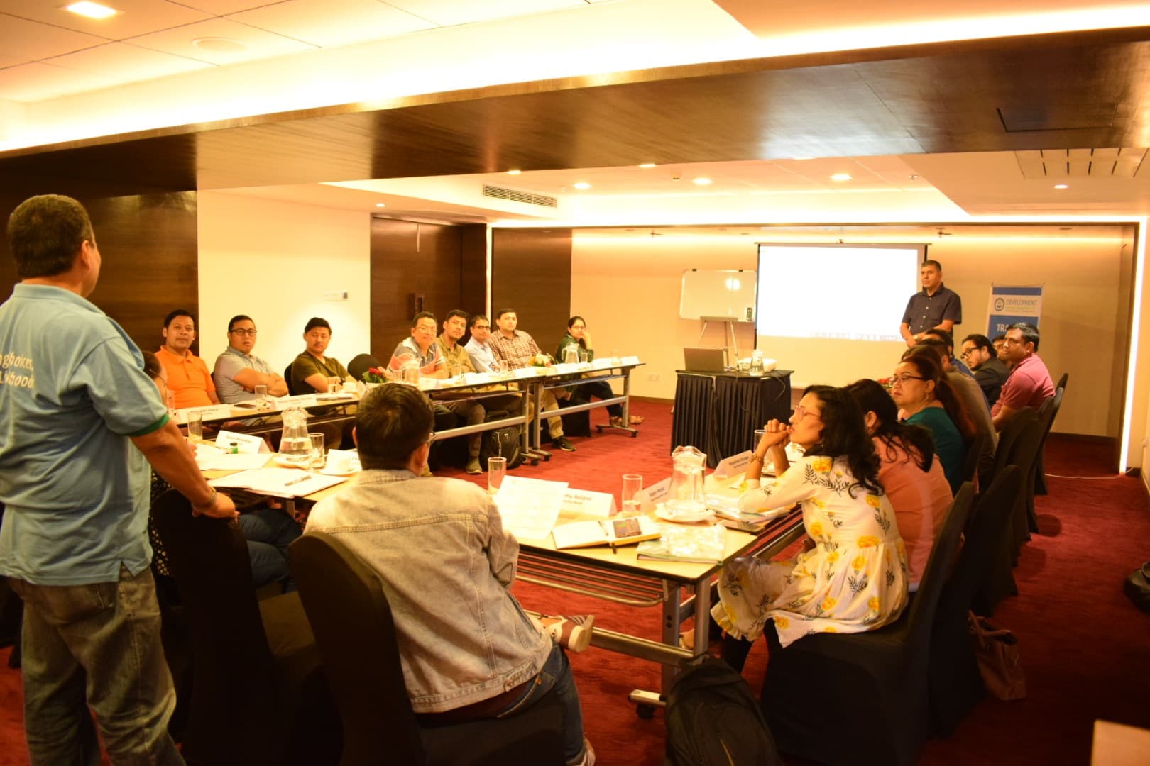 A trainer addressing participants in a conference room