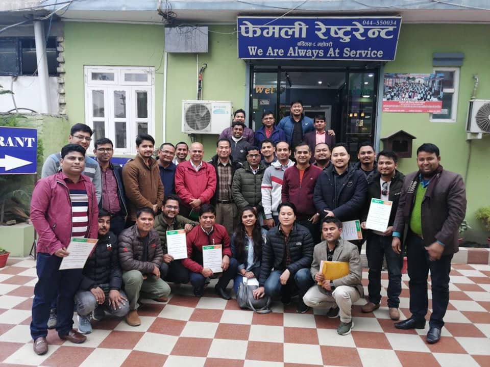 A large participant group posing beneath a training banner